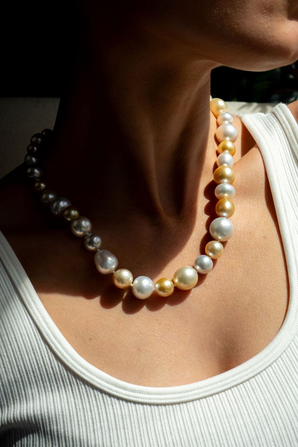 Woman in tank top wearing saltwater pearls in cream and goldd gold 